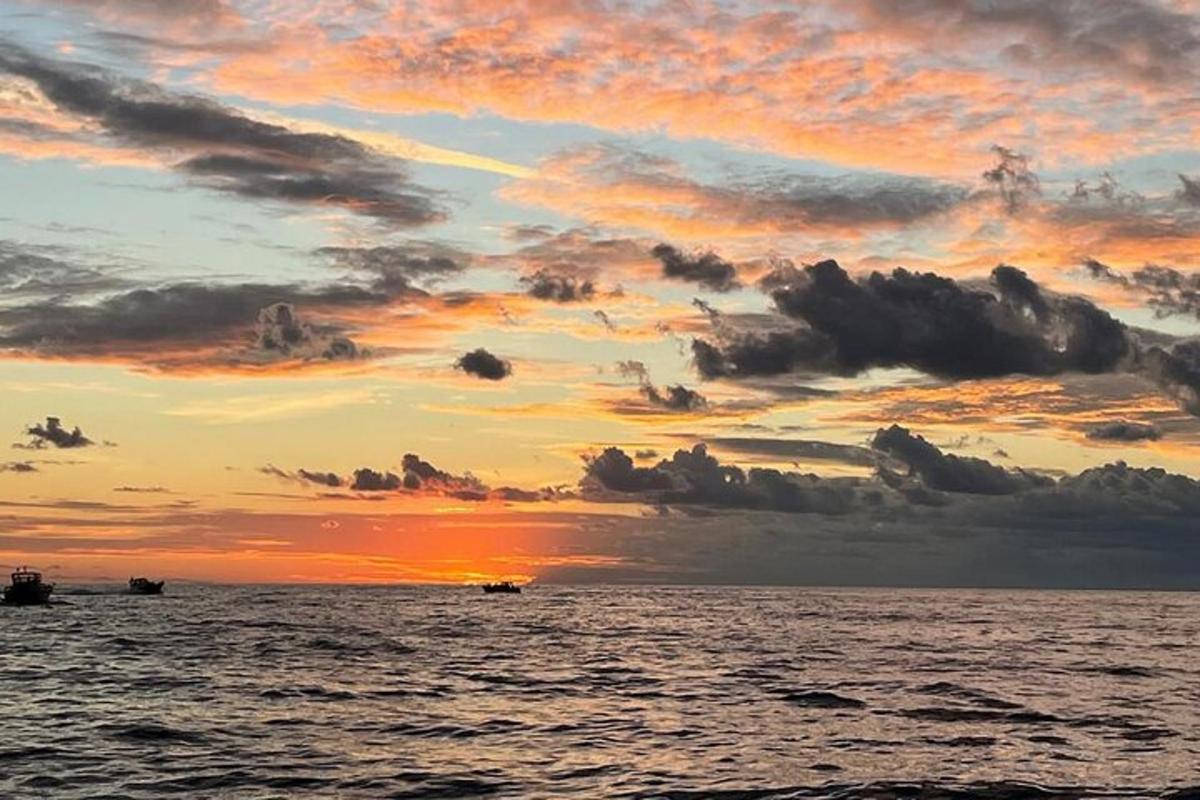 un tramonto sull'oceano con due barche in acqua