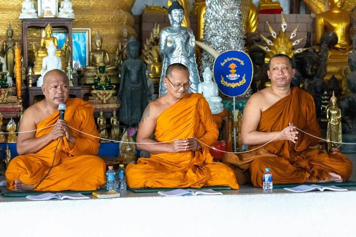 tatlong monghe na nakaupo sa isang templo na may mikropono