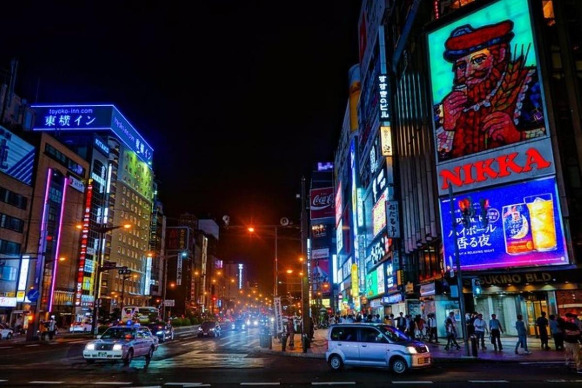 a busy city street at night with neon signs