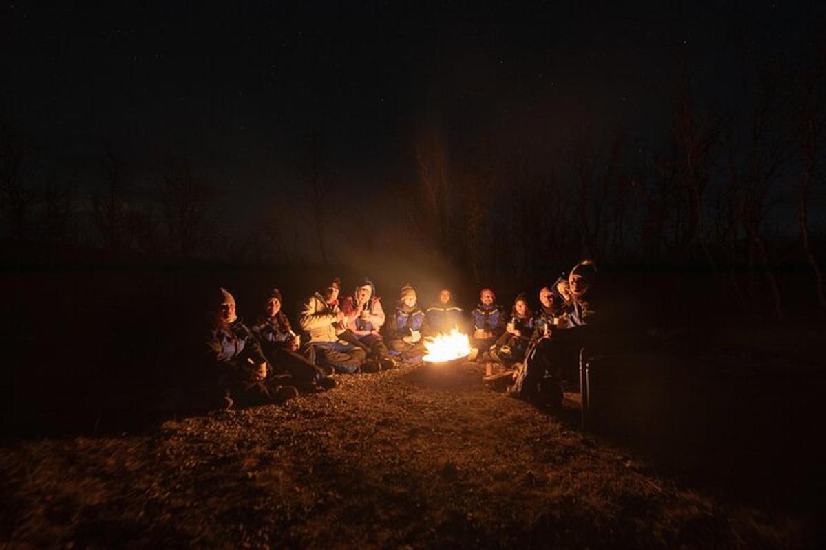 Un grupo de personas sentadas alrededor de un fuego por la noche.