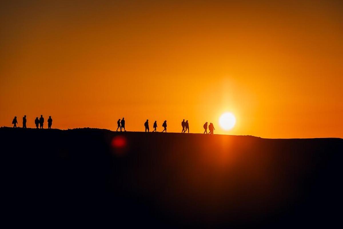 un gruppo di persone in piedi su una collina al tramonto