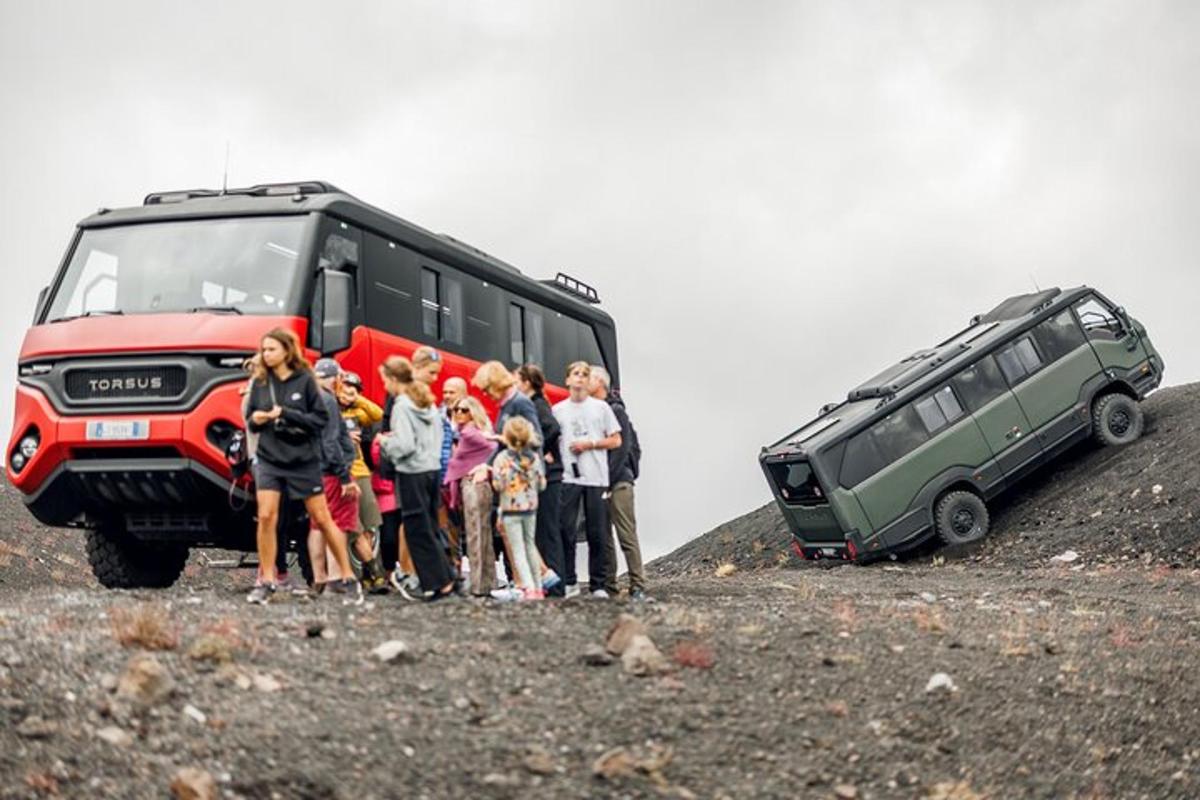 grupė žmonių, stovinčių šalia autobuso ant kalvos