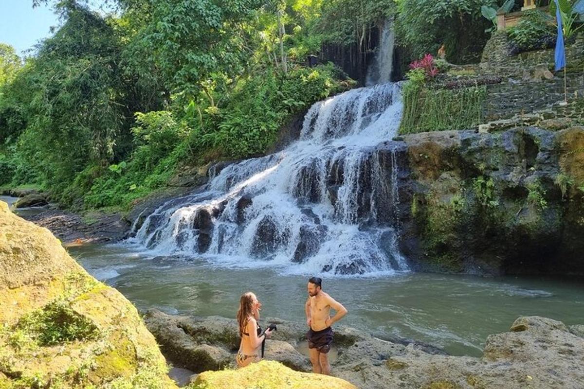 dalawang taong nakatayo sa isang ilog na may talon