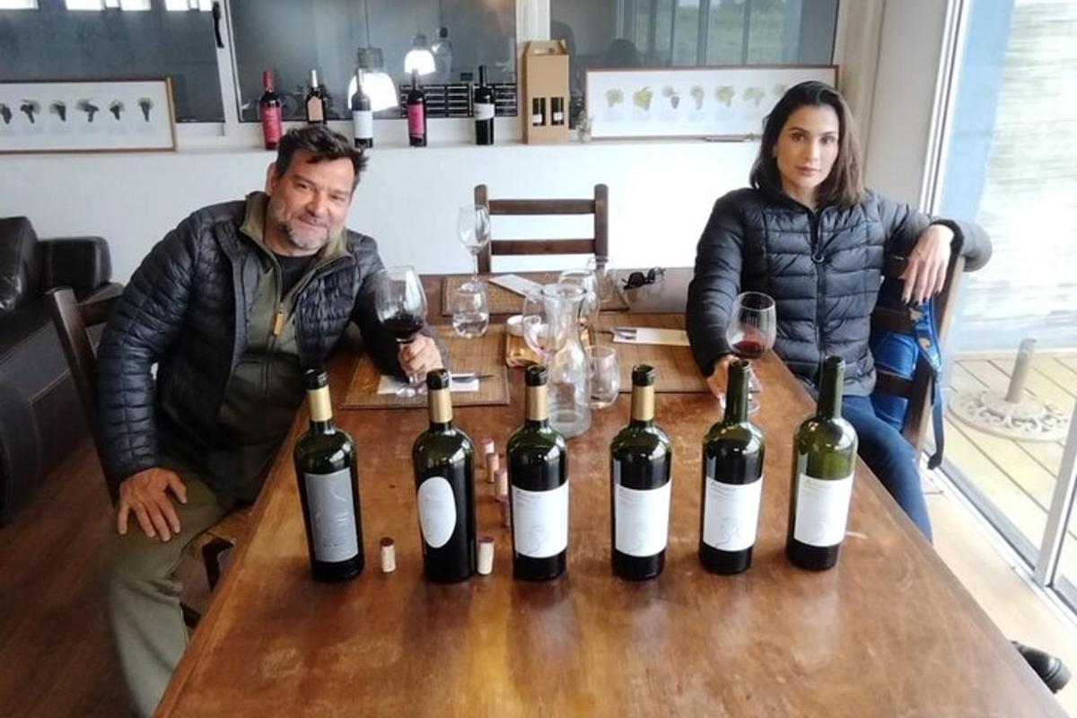 um homem e uma mulher sentados à mesa com garrafas de vinho