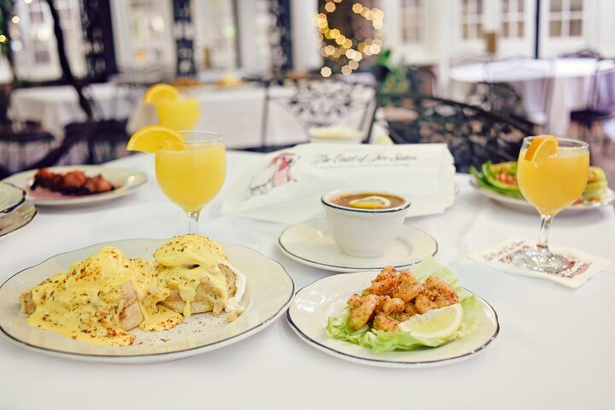 una mesa con platos de comida y vasos de jugo de naranja