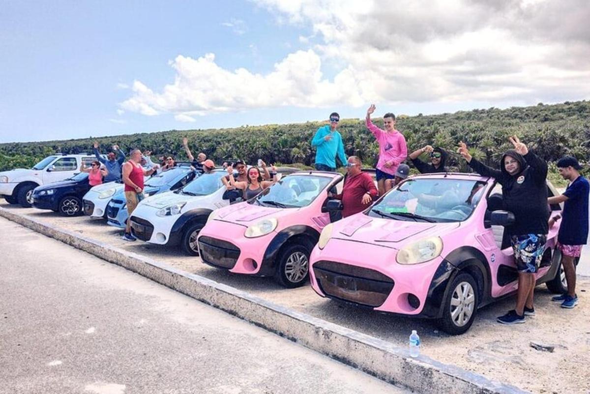 um grupo de pessoas em pé ao lado de seus carros rosa