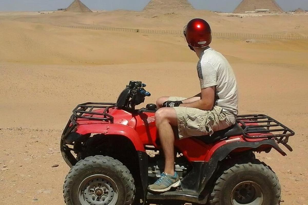 un home conduint un quad vermell al desert