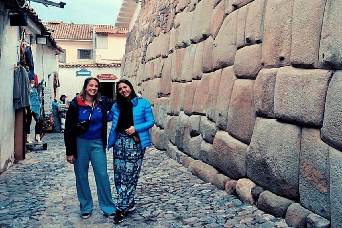Dos mujeres de pie junto a un muro de piedra