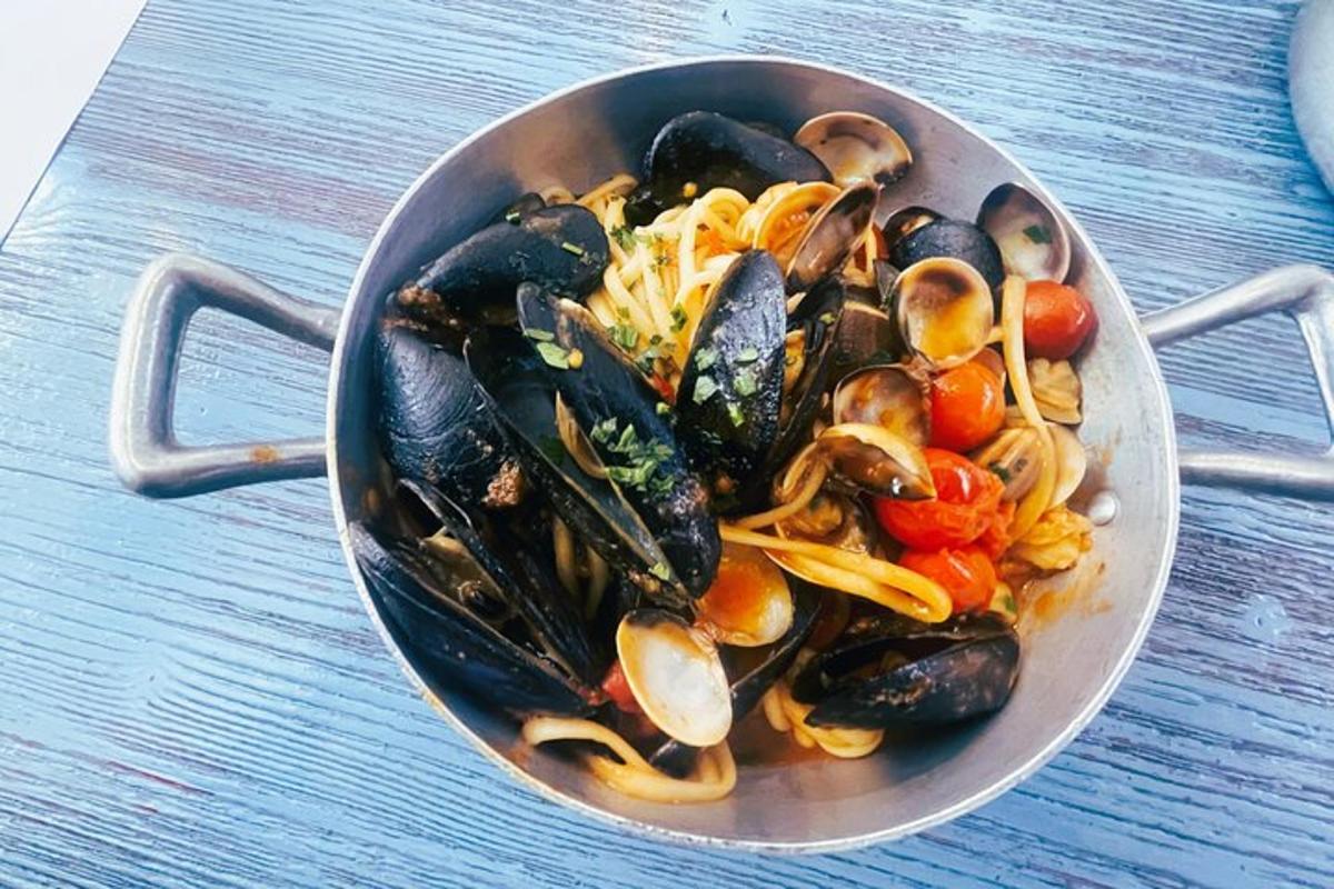 Una sartén llena de mejillones y verduras sobre una mesa.