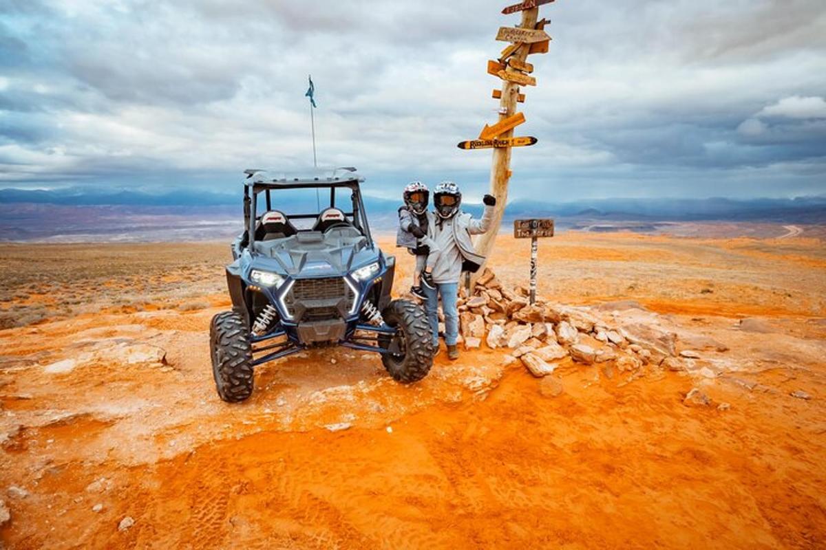 two people standing in front of a vehicle in the desert