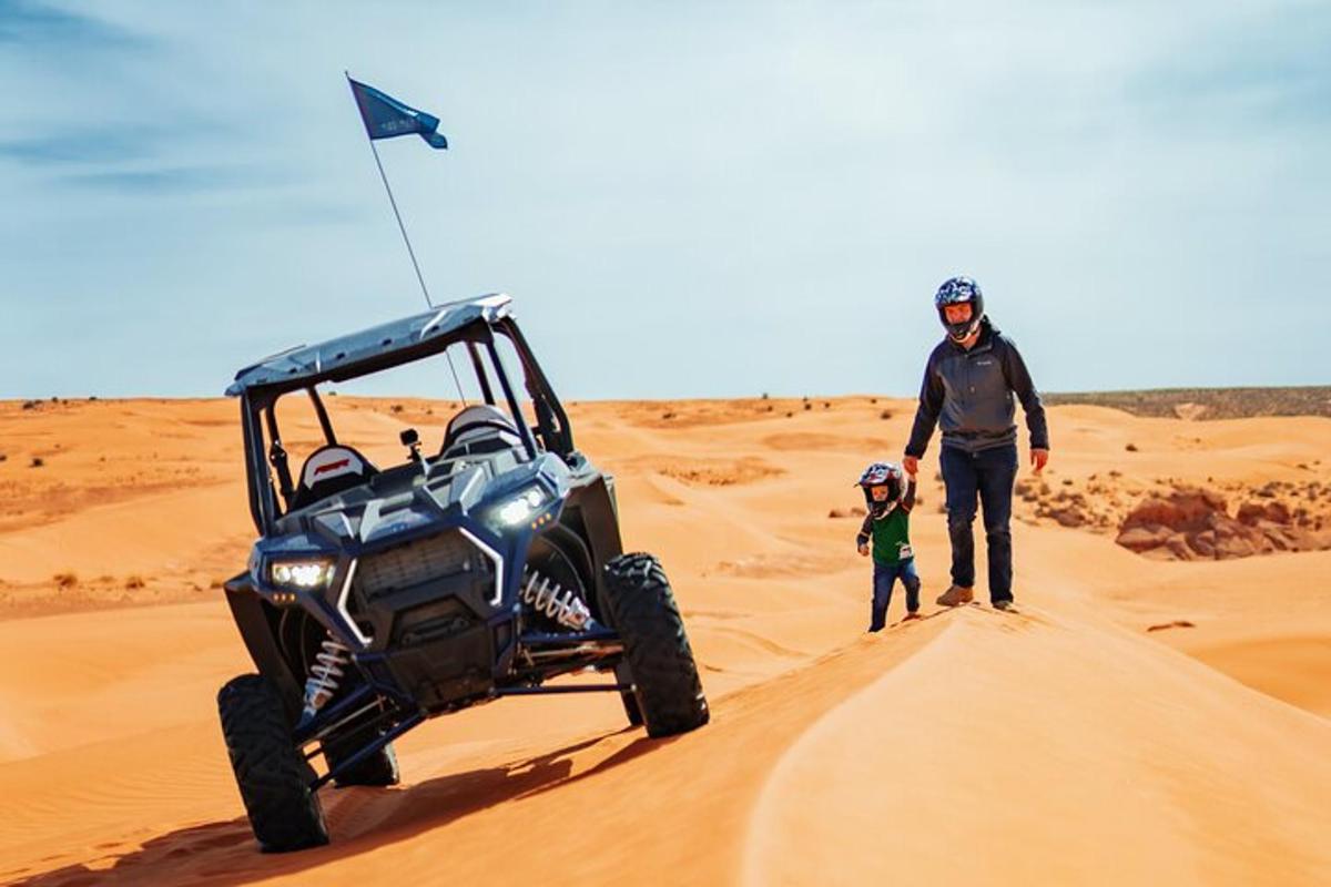 a man and a child standing in the desert with a vehicle