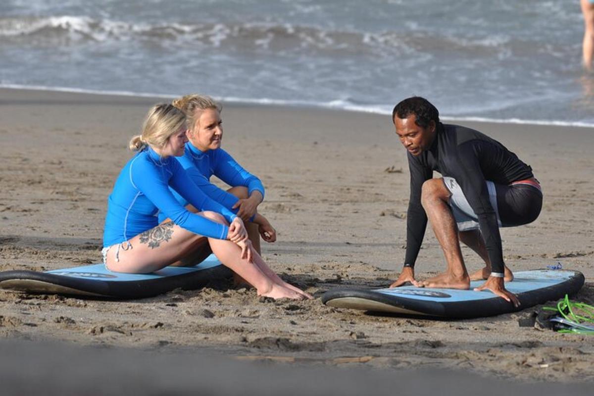 Tres personas sentadas en tablas de surf en la playa