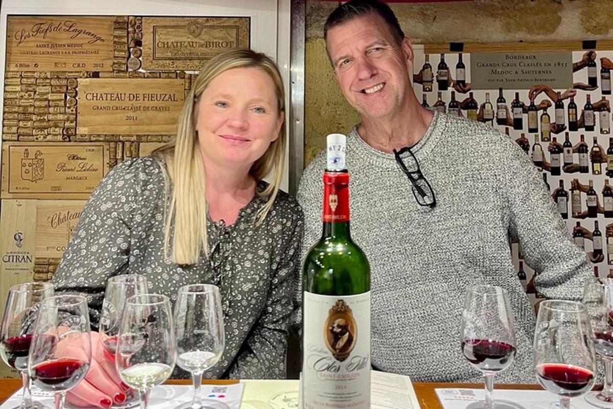 un bărbat și o femeie așezați la o masă cu o sticlă de vin