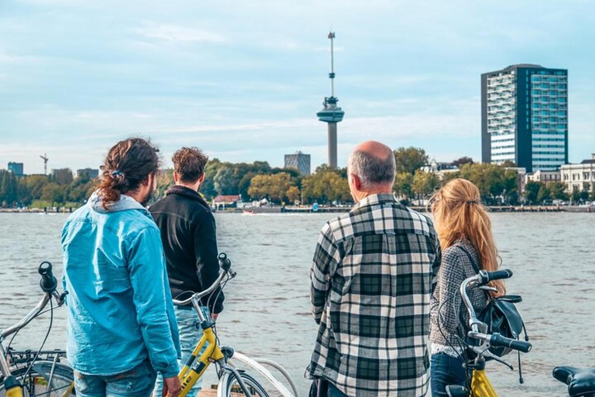 grupė žmonių, stovinčių prie vandens su dviračiais