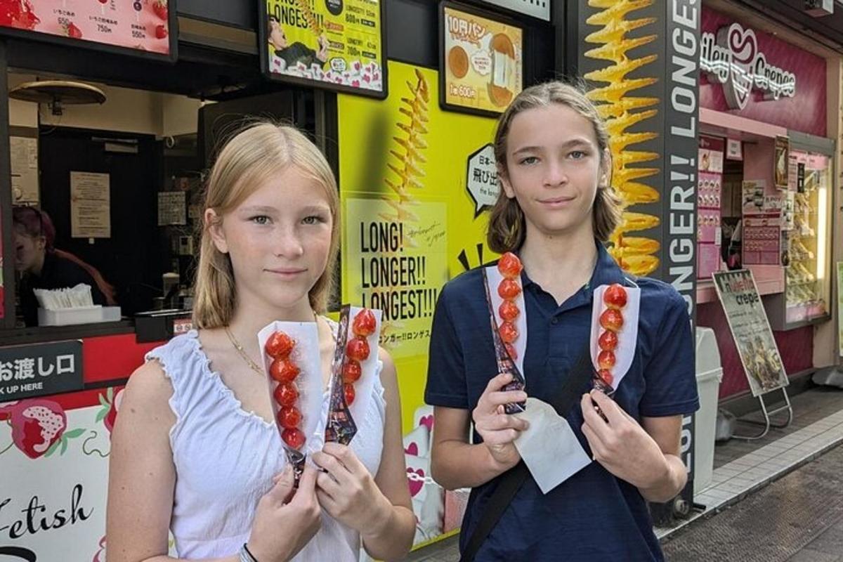 dalawang batang babae na nakatayo sa harap ng isang tindahan na may hawak na mga hotdog
