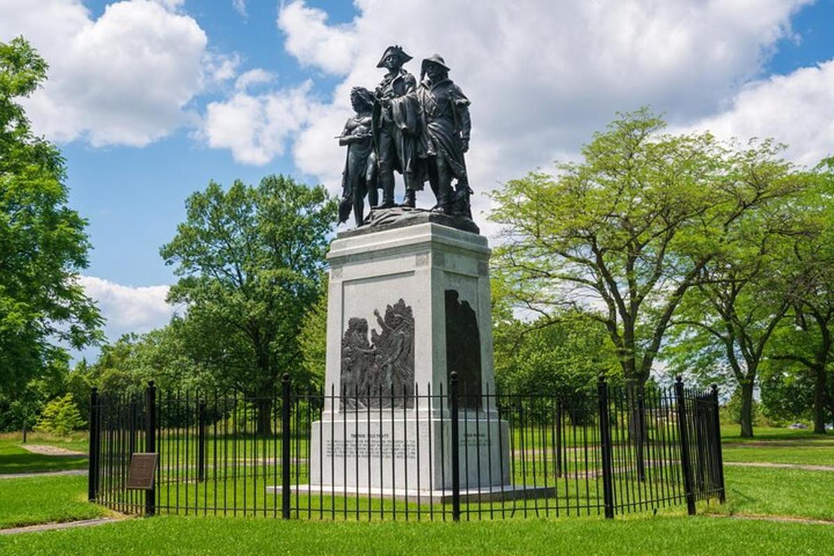 a statue in a park next to a fence