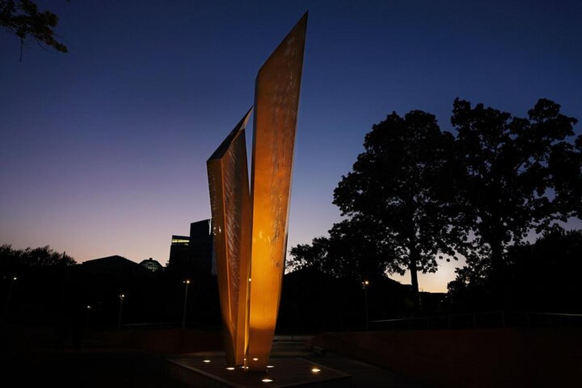 a tall metal sculpture in front of a tree