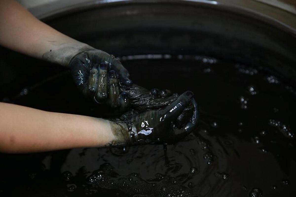 a person in black gloves cooking in a pot