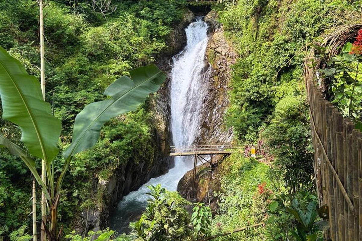 a waterfall on the side of a mountain with a bridge