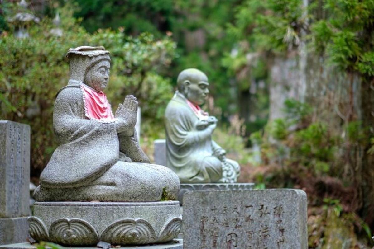 two statues of people sitting onestones in a cemetery