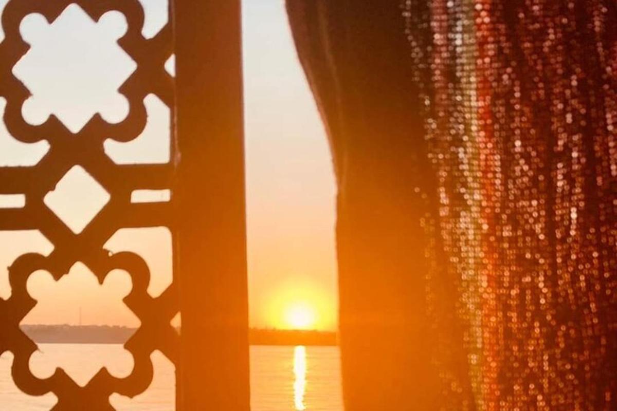 Una vista del atardecer a través de una ventana con cortina.
