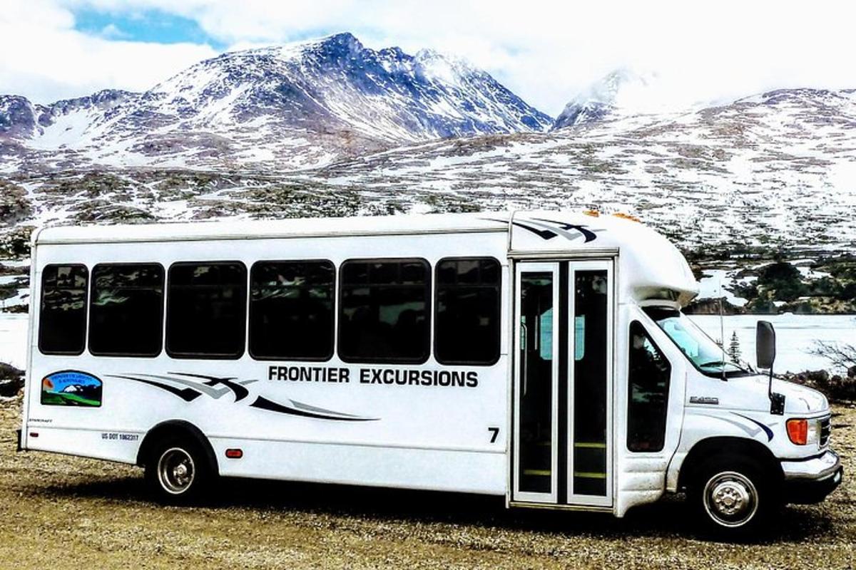 a white bus parked in front of a snow covered mountain