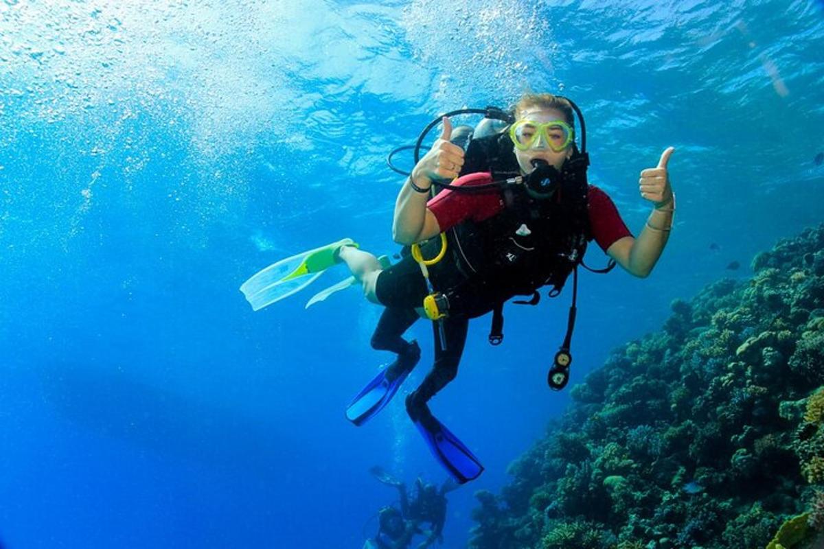 een persoon die een duim omhoog steekt terwijl hij in de oceaan duikt