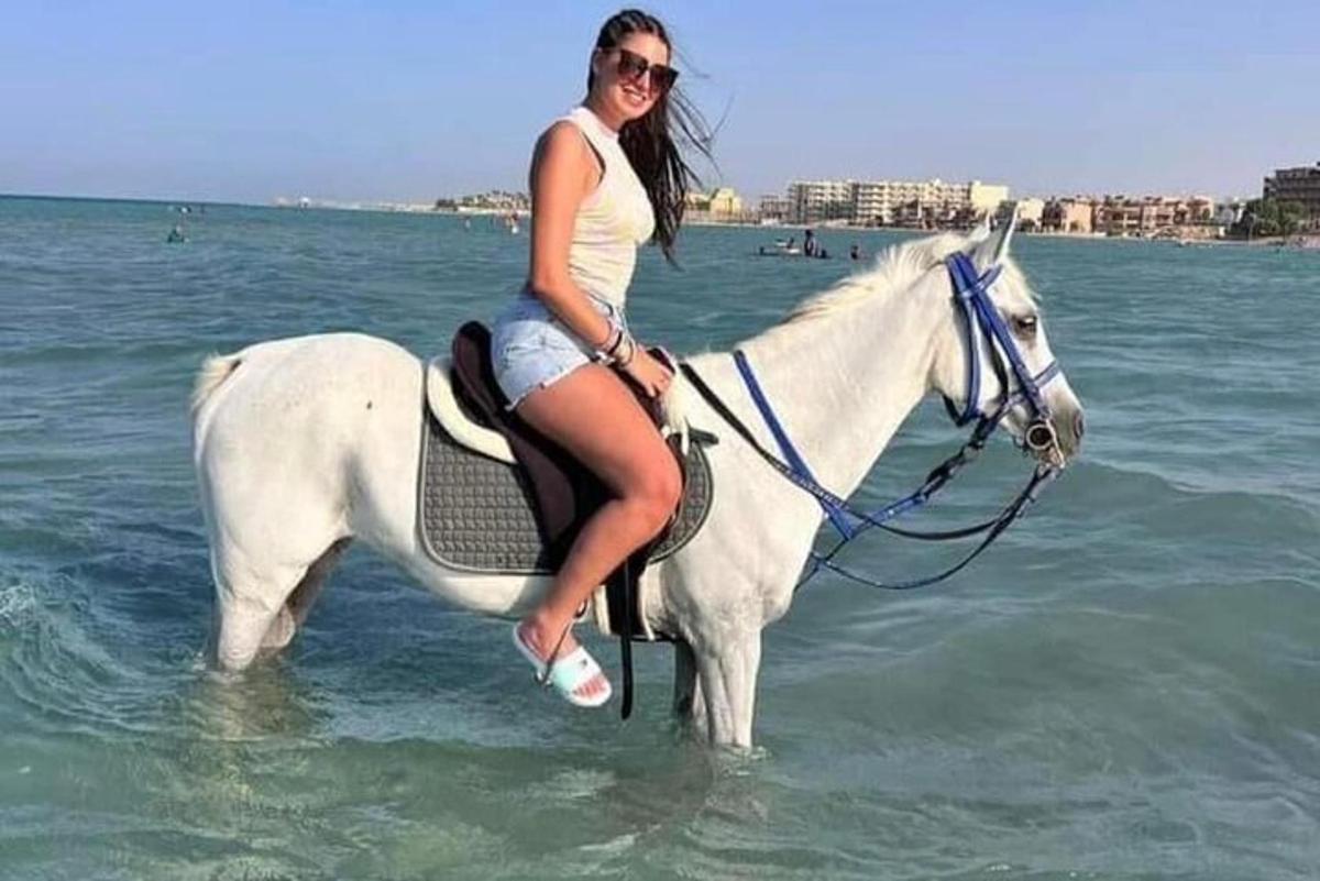 žena jedoucí na bílém koni v oceánu