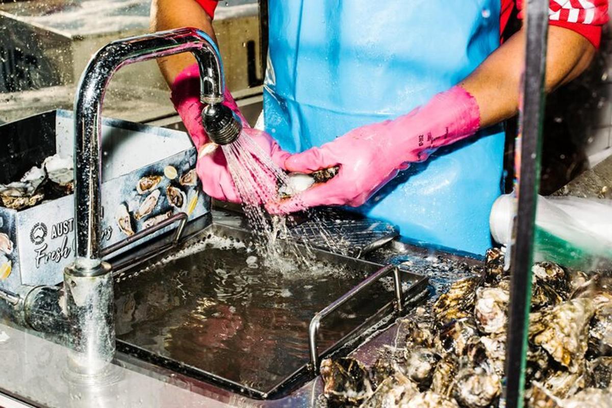 una persona con guanti rosa che lava il cibo in un lavandino