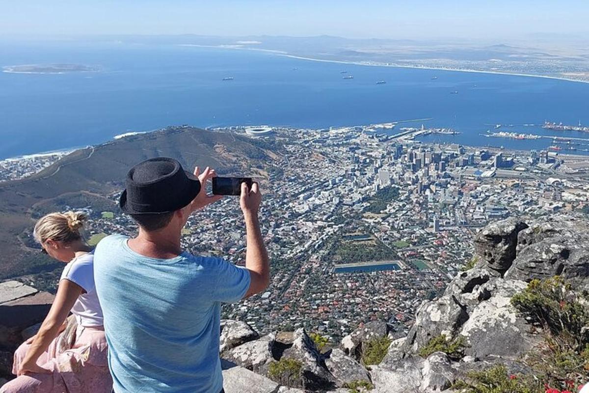 a man taking a picture of a city from a mountain