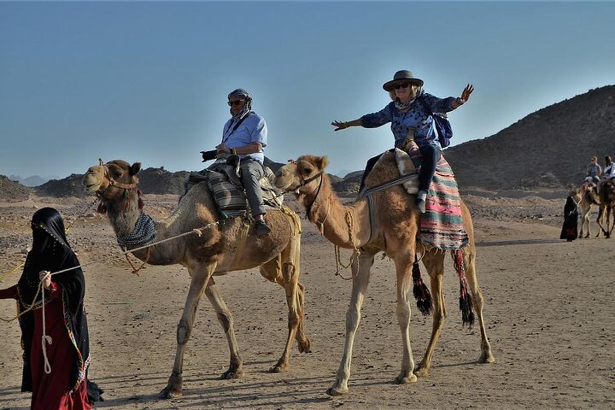 two men riding on the backs of camels in the desert