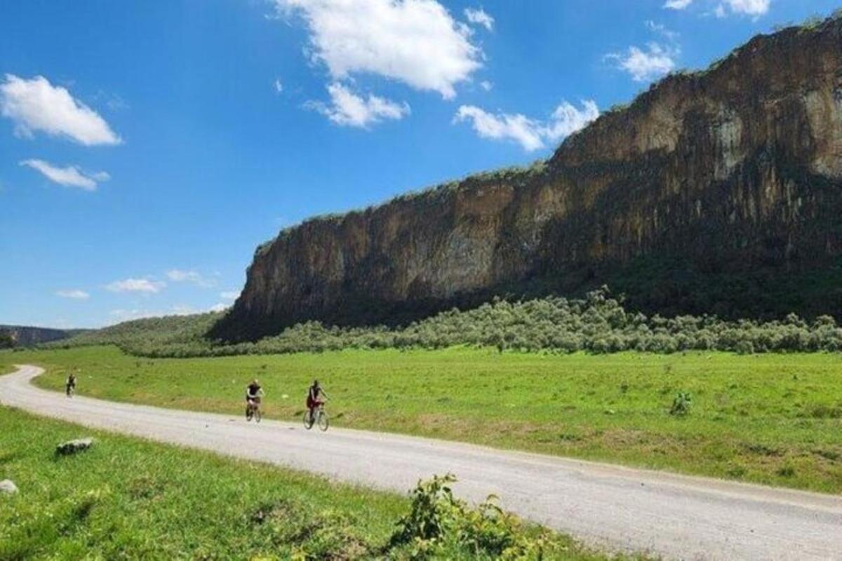 two people riding bikes on a road near a mountain