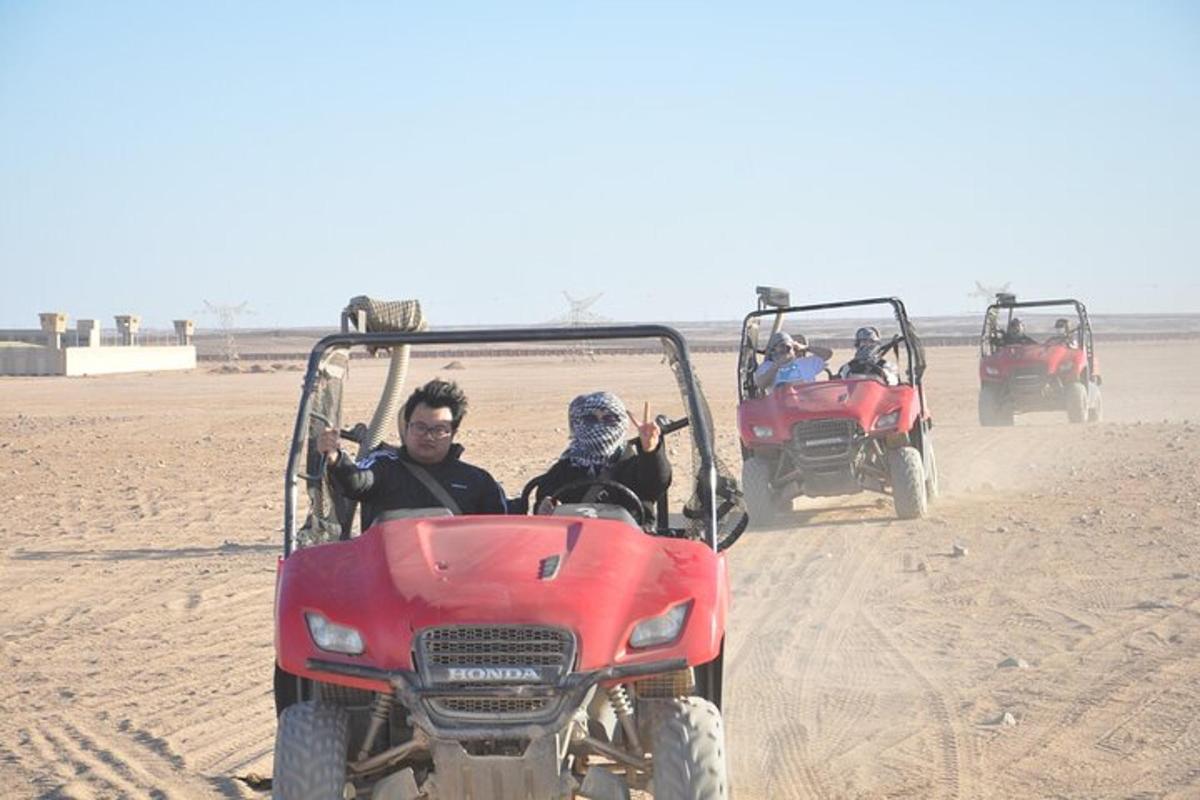 Un grupo de personas viajando en vehículos todo terreno en el desierto.