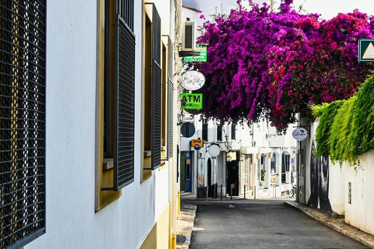 an alley with purple flowers hanging from buildings