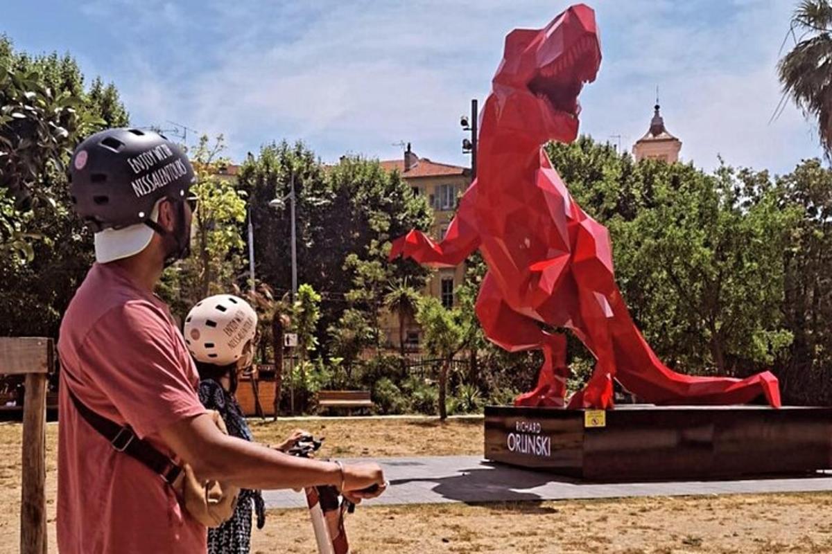 a man and a child wearing helmets standing next to a statue