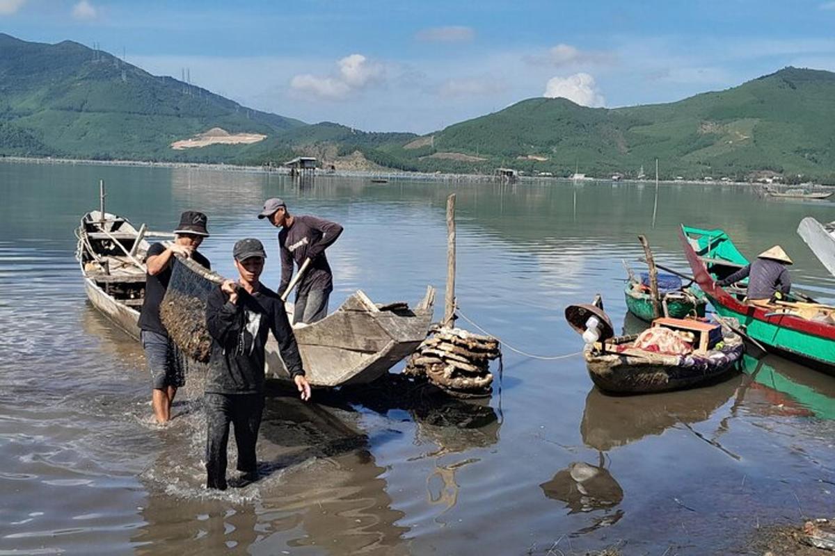 một nhóm người đứng trong nước cạnh một chiếc thuyền