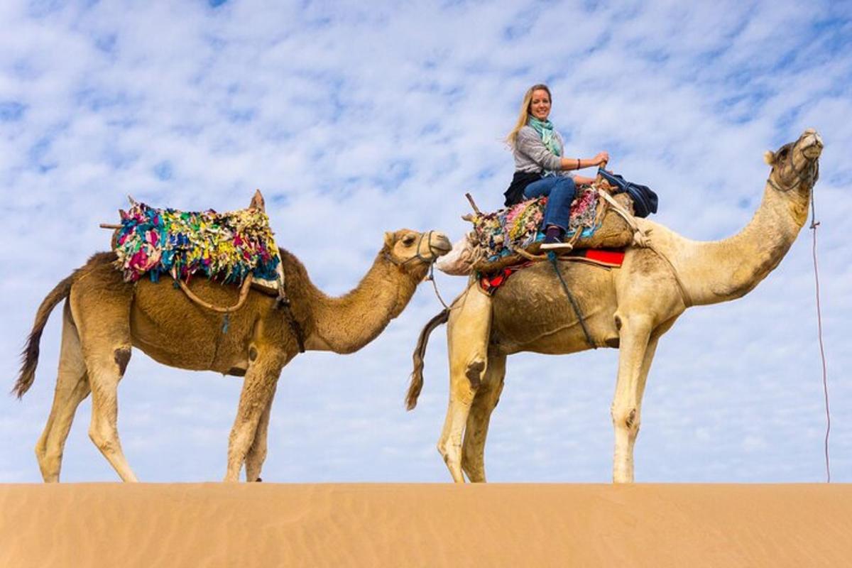 uma mulher montada em um camelo no deserto