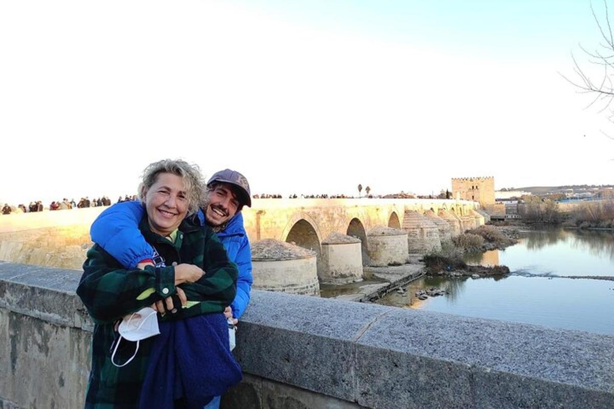 two people standing on a bridge over a river