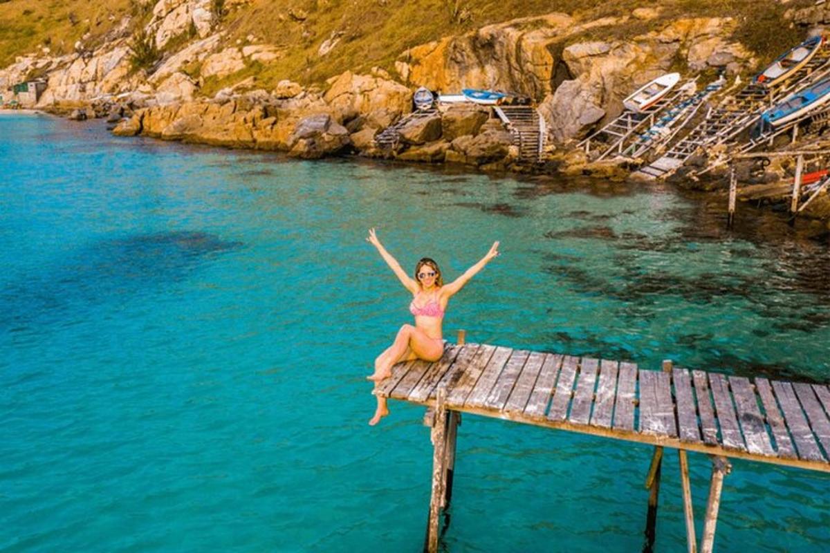 Μια γυναίκα με μπικίνι κάθεται σε μια προβλήτα στο νερό