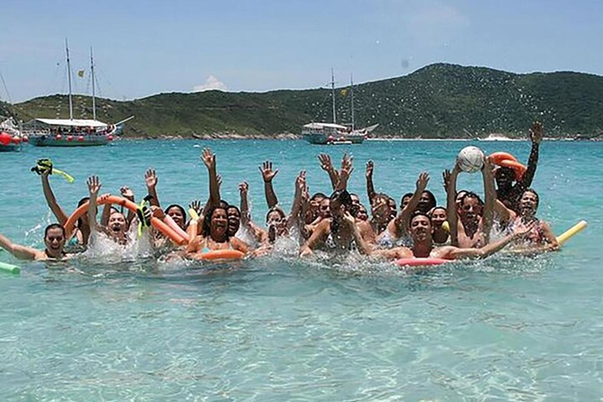 Un grupo de personas en el agua con los brazos en el aire.