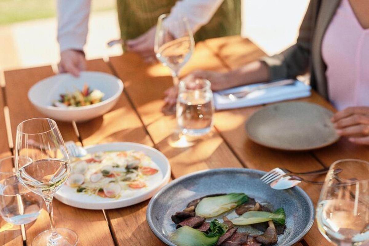 a wooden table with plates of food and wine glasses