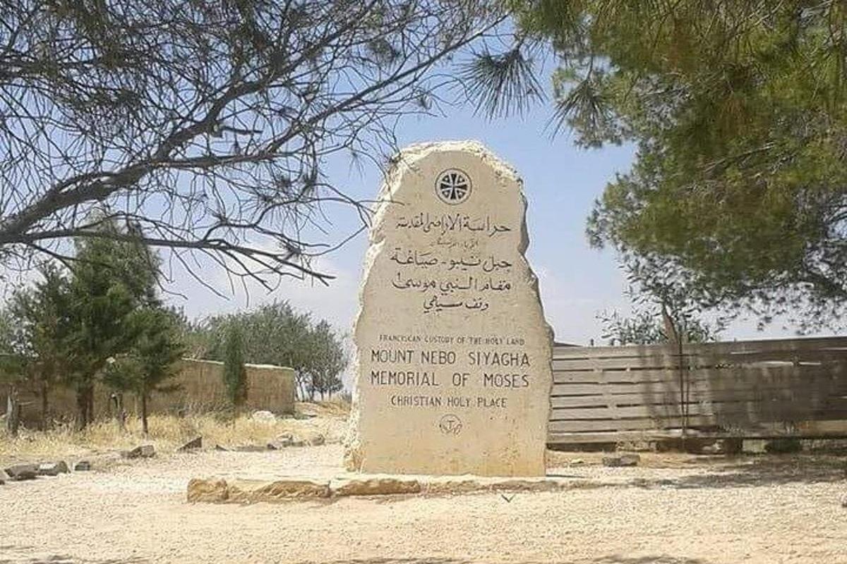 a monument with writing on it in front of a fence