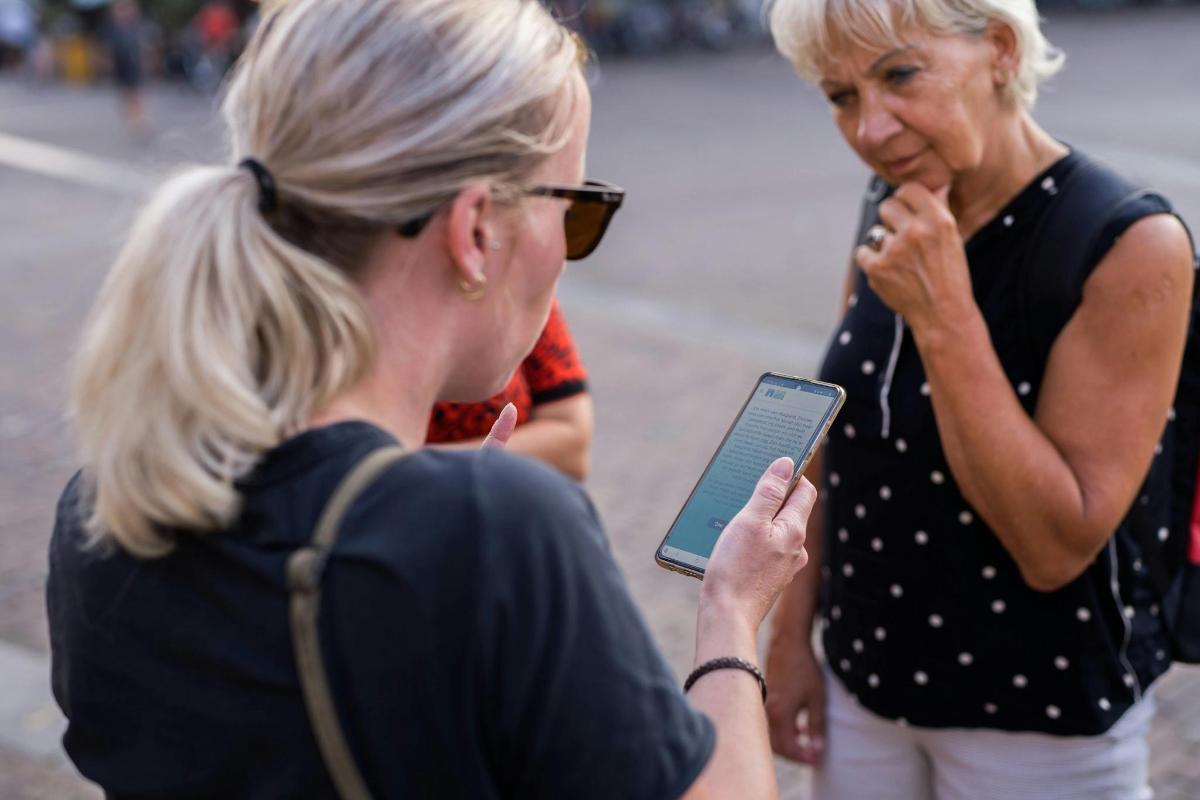 dvě ženy stojící vedle sebe a dívající se na tablet