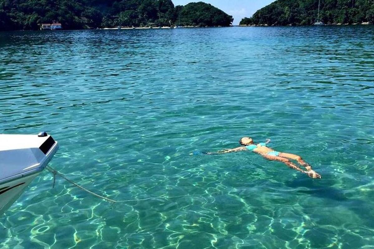 una mujer flotando en el agua junto a un barco