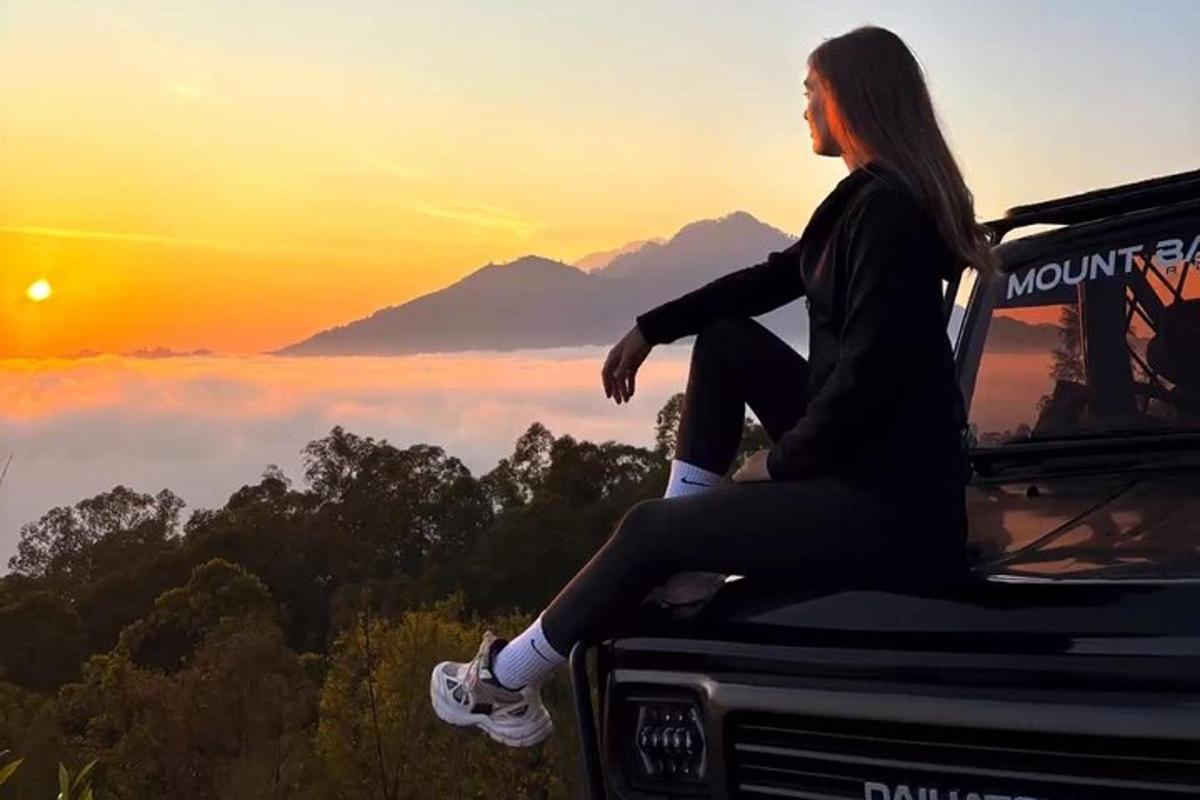 una donna seduta sul davanti di un camion che guarda il tramonto