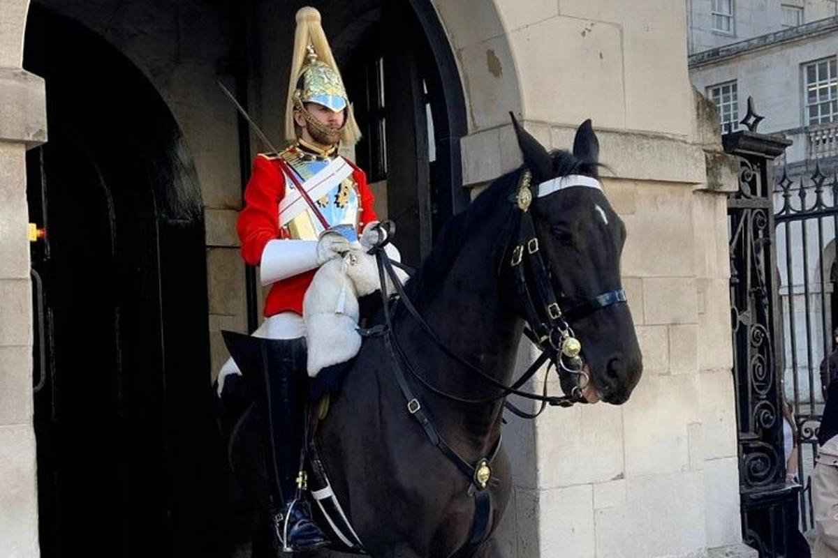 Un hombre uniformado a caballo frente a un edificio.