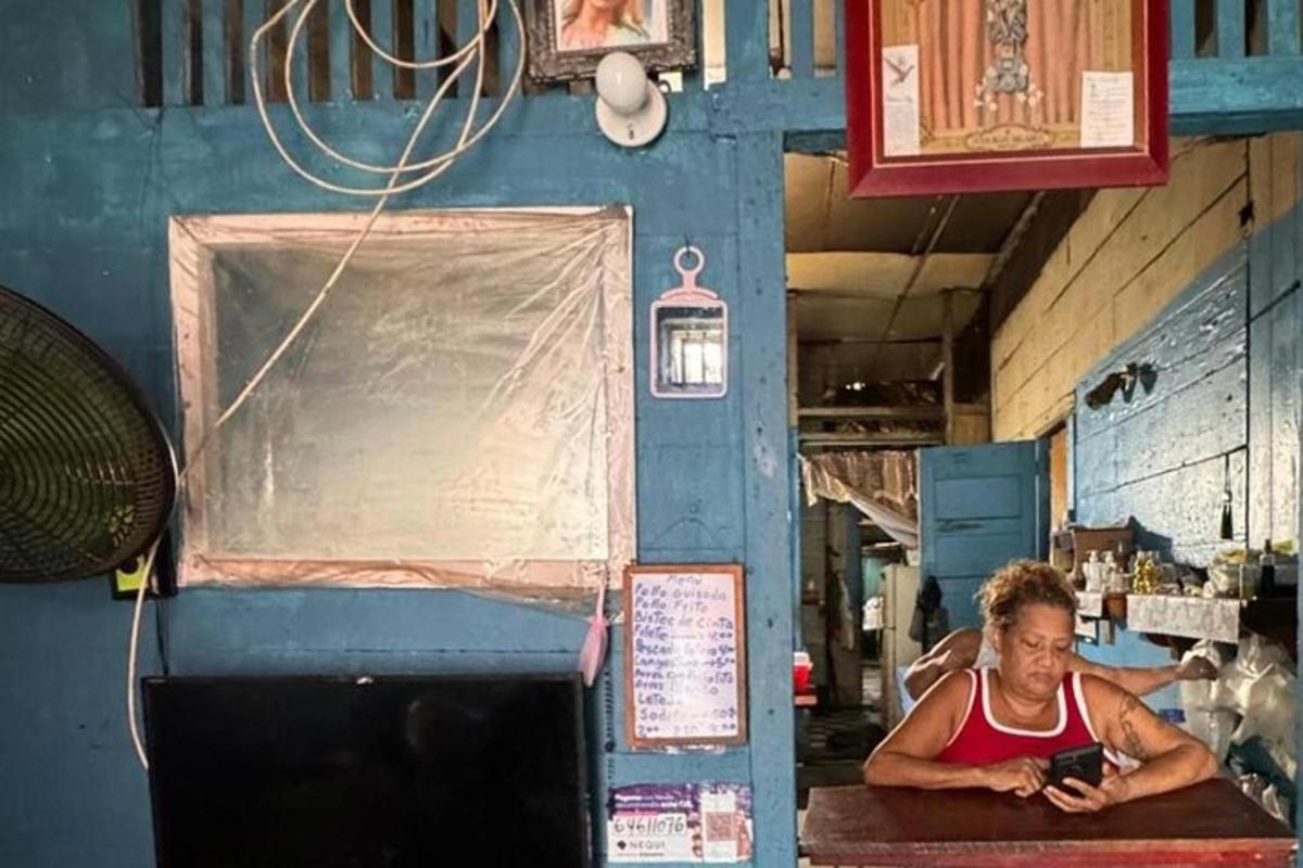 een vrouw die aan een tafel zit en naar een mobiele telefoon kijkt