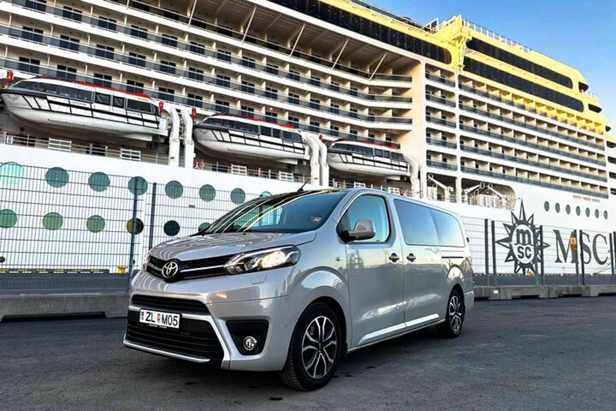 un furgone argentato parcheggiato davanti a una nave da crociera