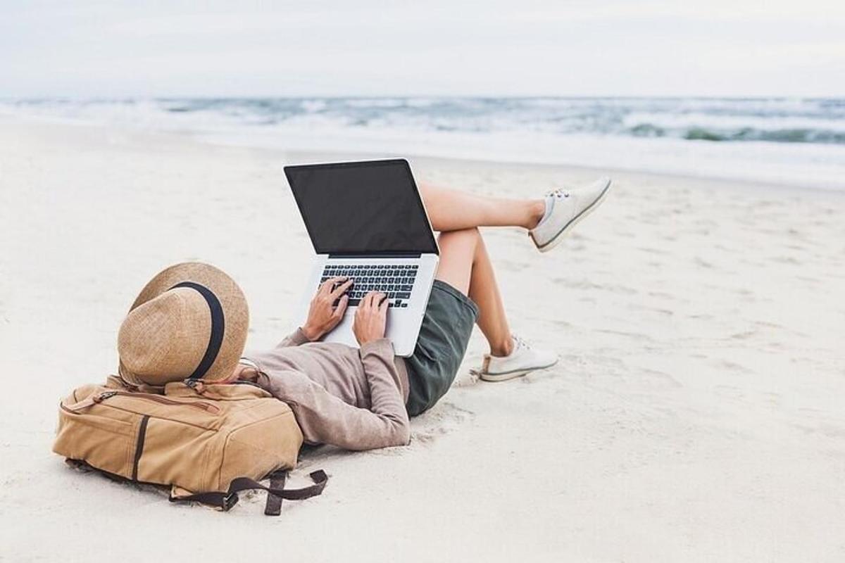 a woman laying on the beach with a laptop