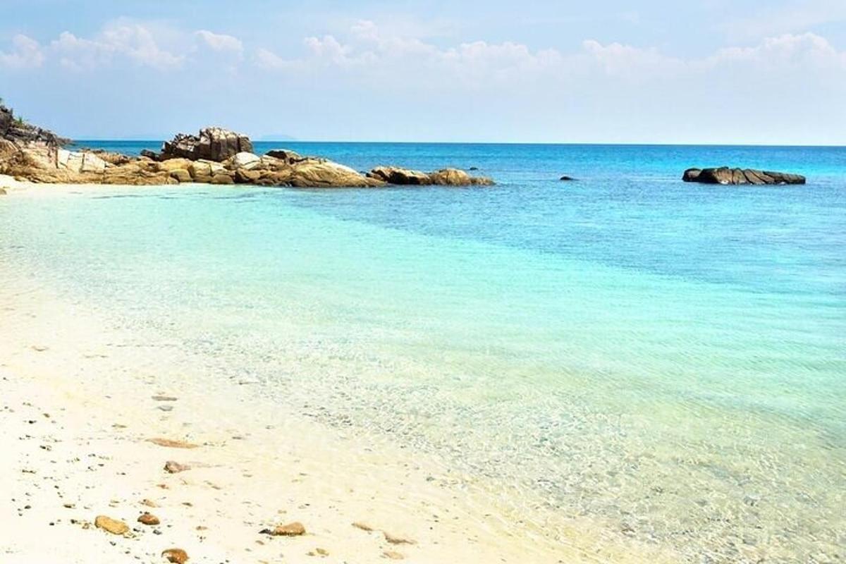 a beach with blue water and rocks in the ocean